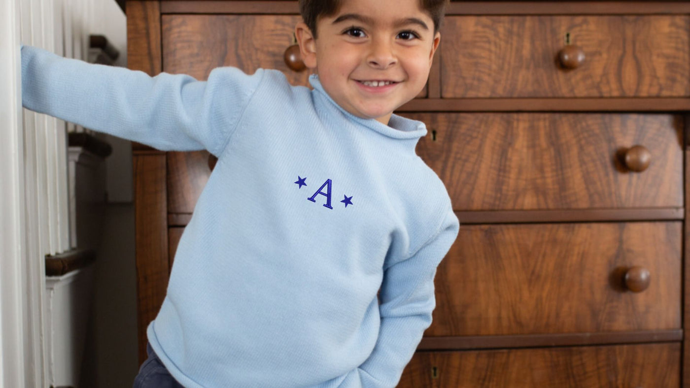 kid swinging from the stairs in his monogrammed sweater