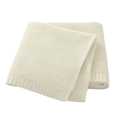 Folded cream-colored knitted blanket on a white background