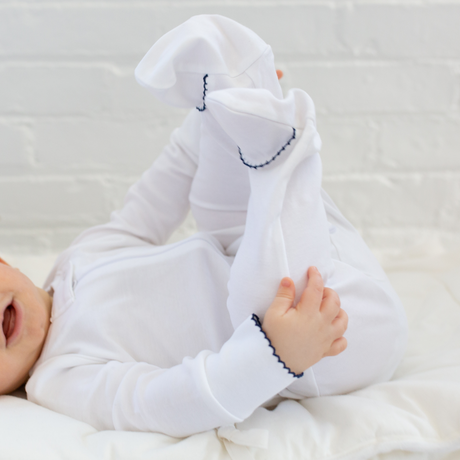 a baby wearing Zipper Romper in White with Navy Picot Trim