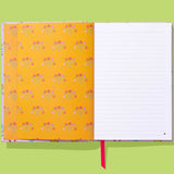 Notebook with floral pattern on yellow cover and lined pages on green background