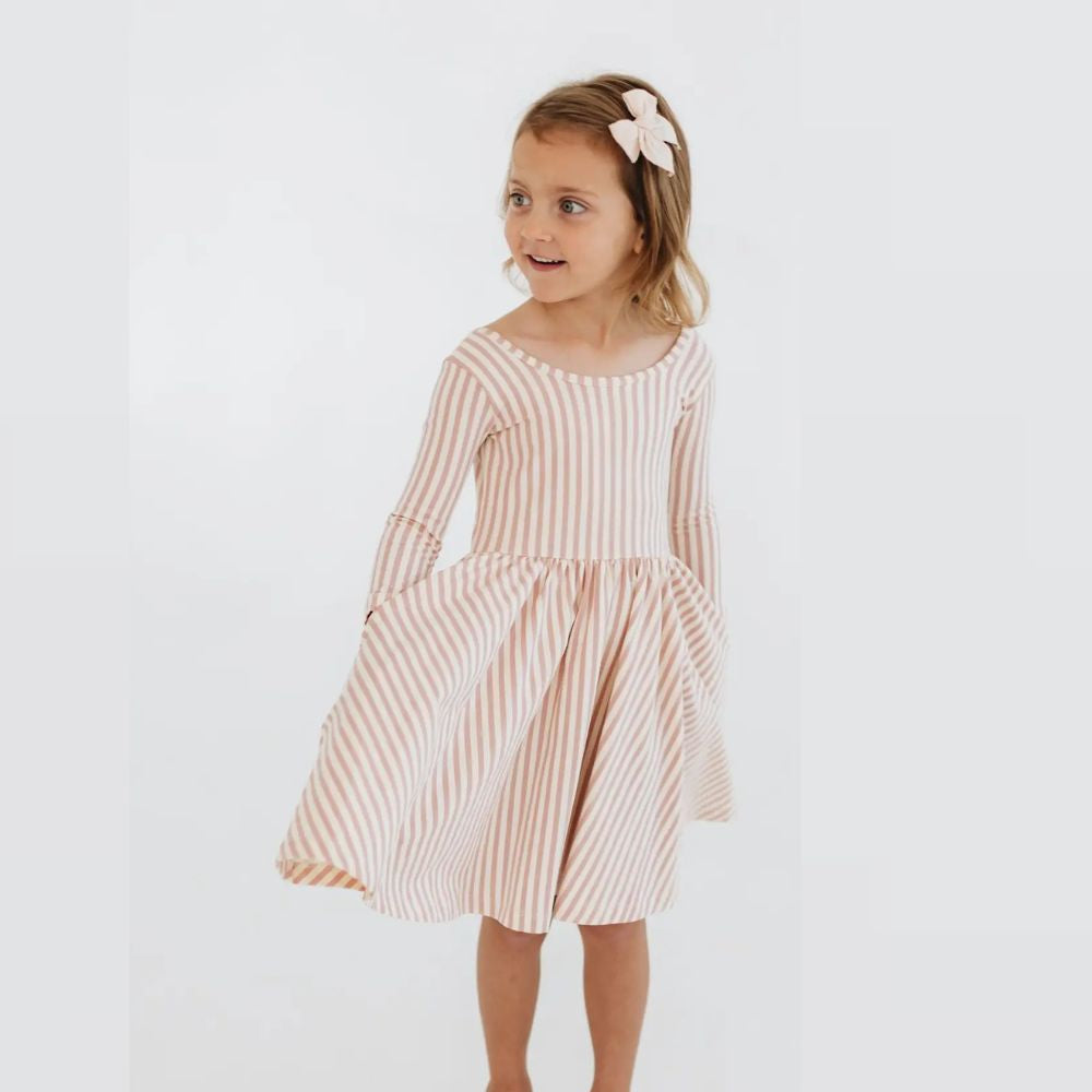 Young girl wearing a pink and white striped dress on a light gray background