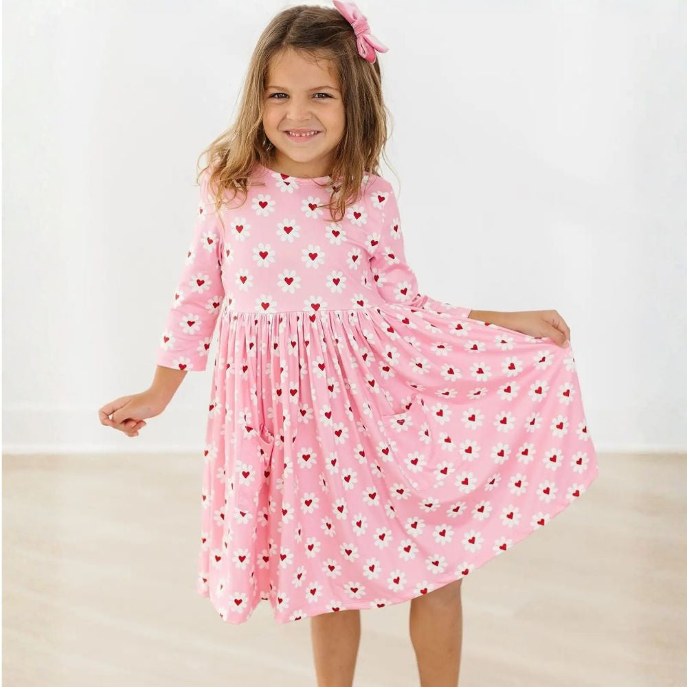 Young girl wearing a pink dress with heart patterns on a white background