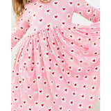 Pink dress with heart and flower pattern worn by a child