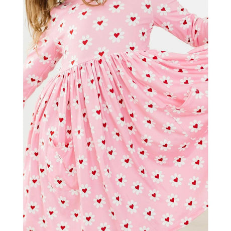Pink dress with heart and flower pattern worn by a child