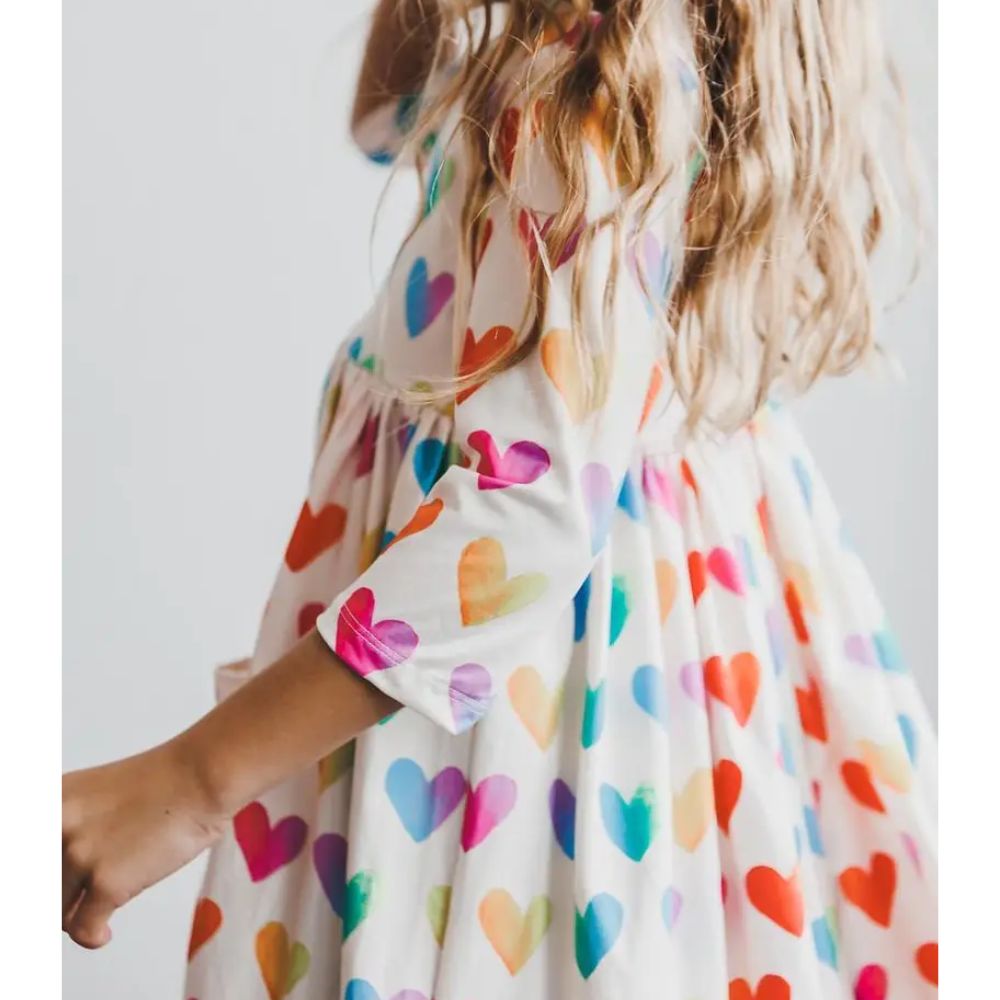 Woman wearing a dress with colorful heart pattern on a plain background