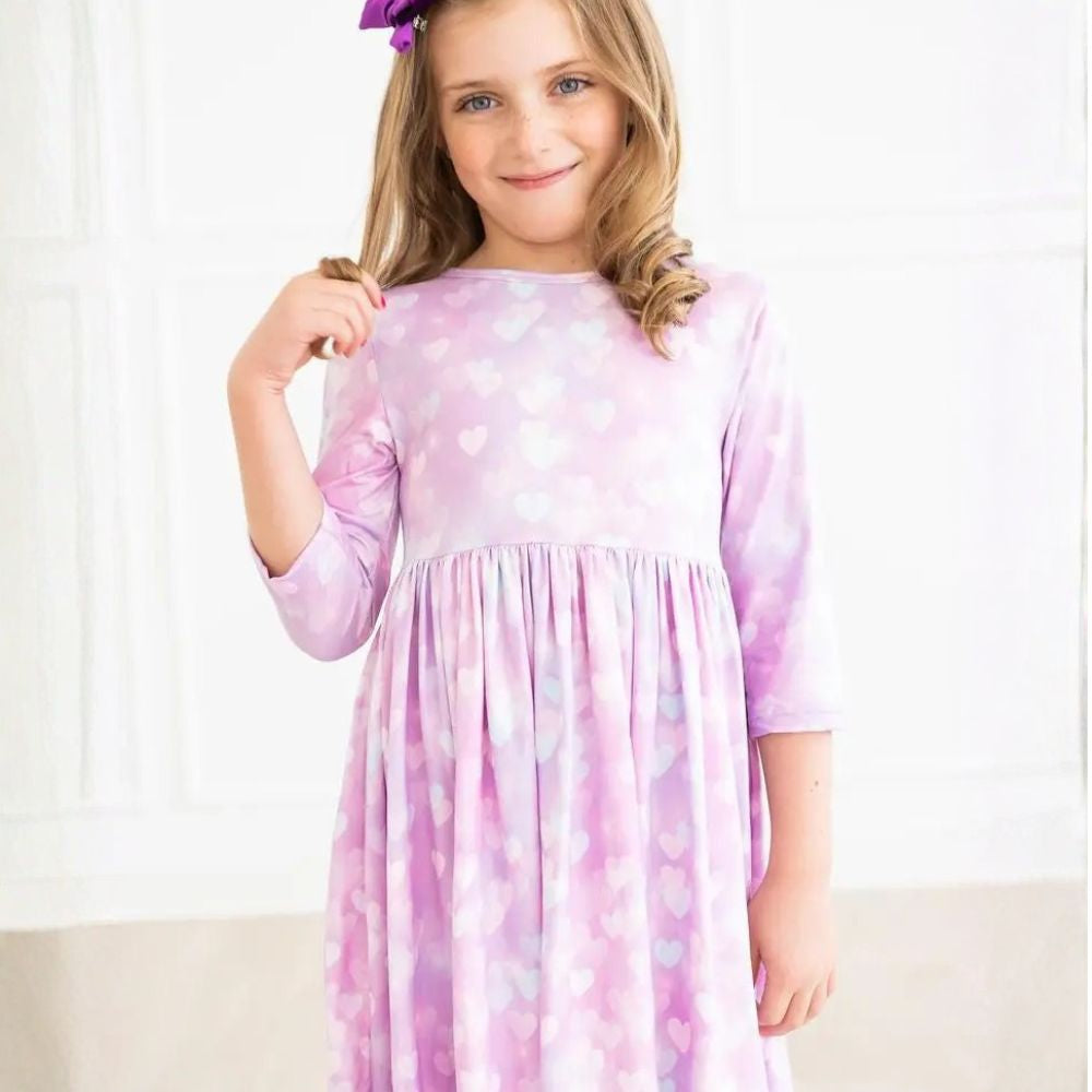 Pink/purple dress with heart patterns worn by a person on a white background