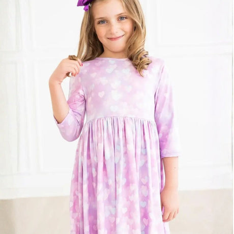 Pink/purple dress with heart patterns worn by a person on a white background