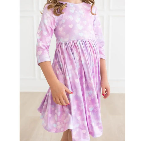 Pink/purple dress with heart patterns worn by a person on a white background