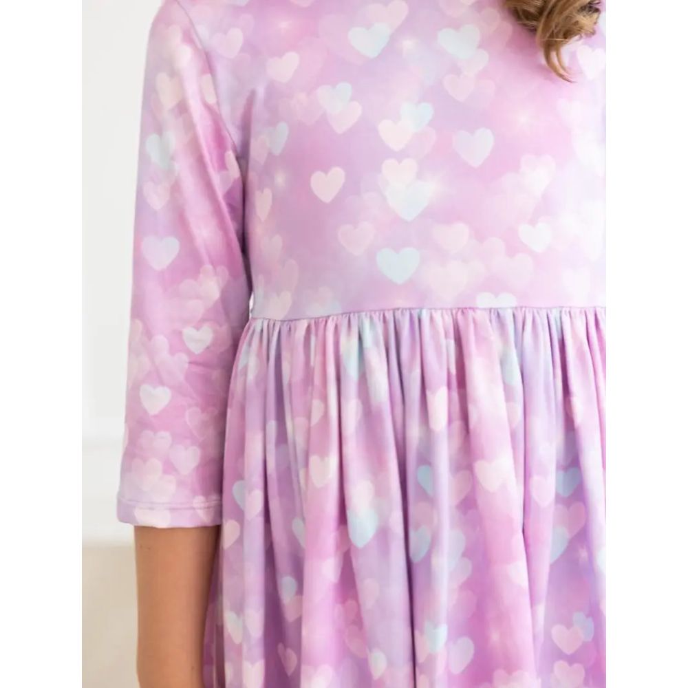 Purple/pink dress with heart pattern worn by a person on a white background
