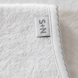 Close-up of a textured white fabric with a brand label on a neutral background
