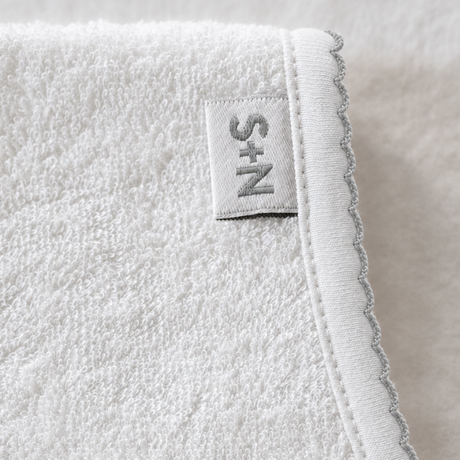 Close-up of a textured white fabric with a brand label on a neutral background