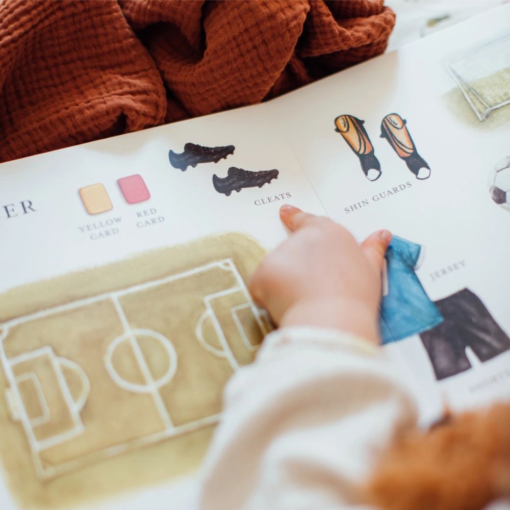 Hand interacting with a soccer field diagram on a book page.