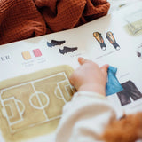 Hand interacting with a soccer field diagram on a book page.