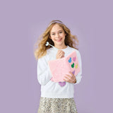 Young girl holding a pink clutch with butterfly designs against a purple background