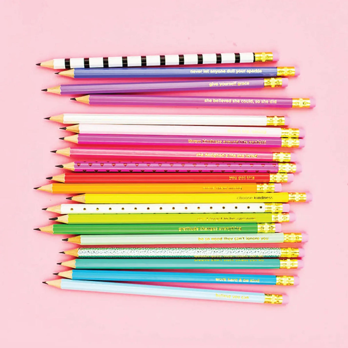 Colorful pencils arranged in a pattern on a pink background