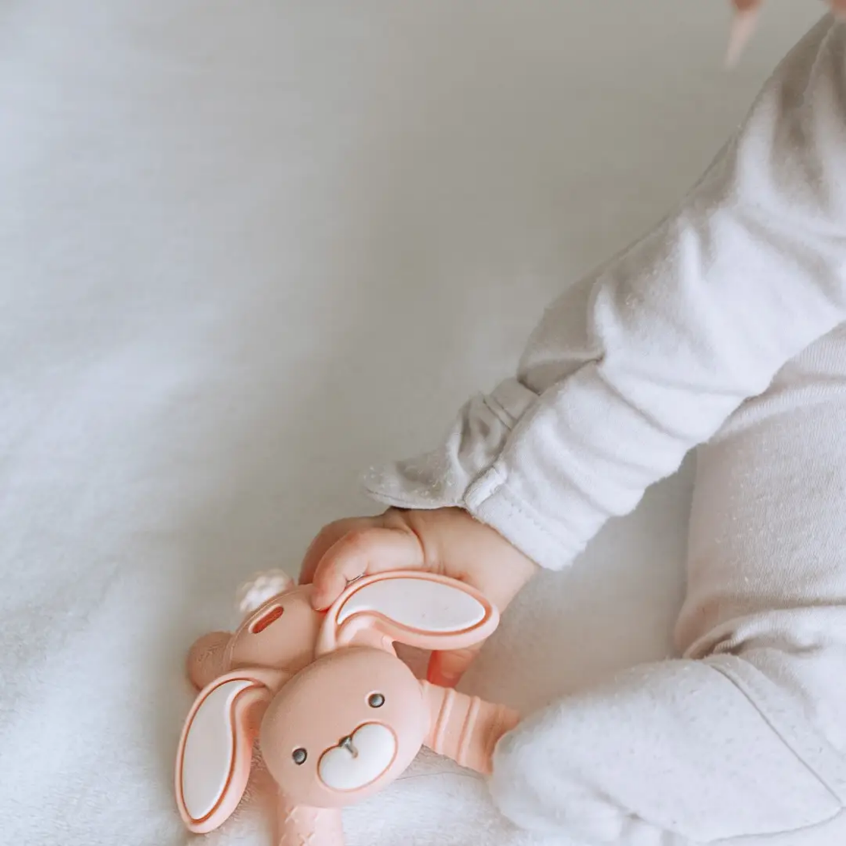 Child holding a pink bunny-shaped toy against a white background