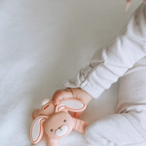 Child holding a pink bunny-shaped toy against a white background