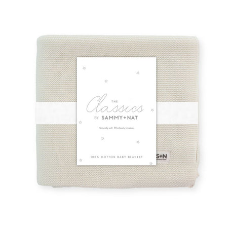 Folded beige baby blanket with a label on a white background