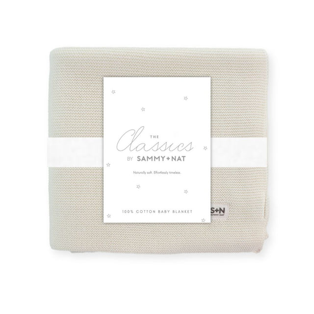 Folded beige baby blanket with a label on a white background