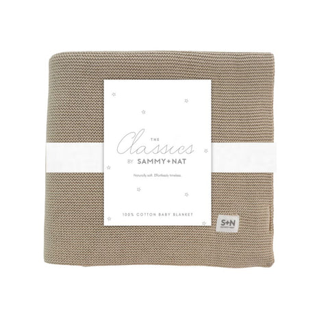 Beige knitted baby blanket with a white label featuring 'Sammy + Nat' branding on a white background.