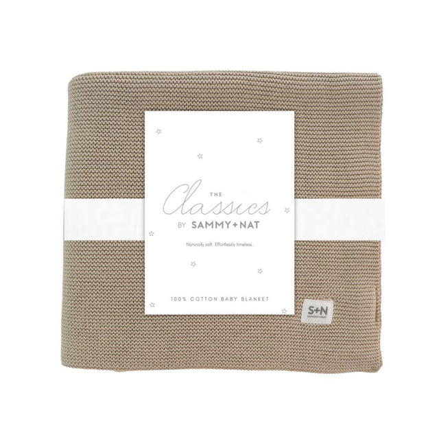 Beige knitted baby blanket with a white label featuring 'Sammy + Nat' branding on a white background.