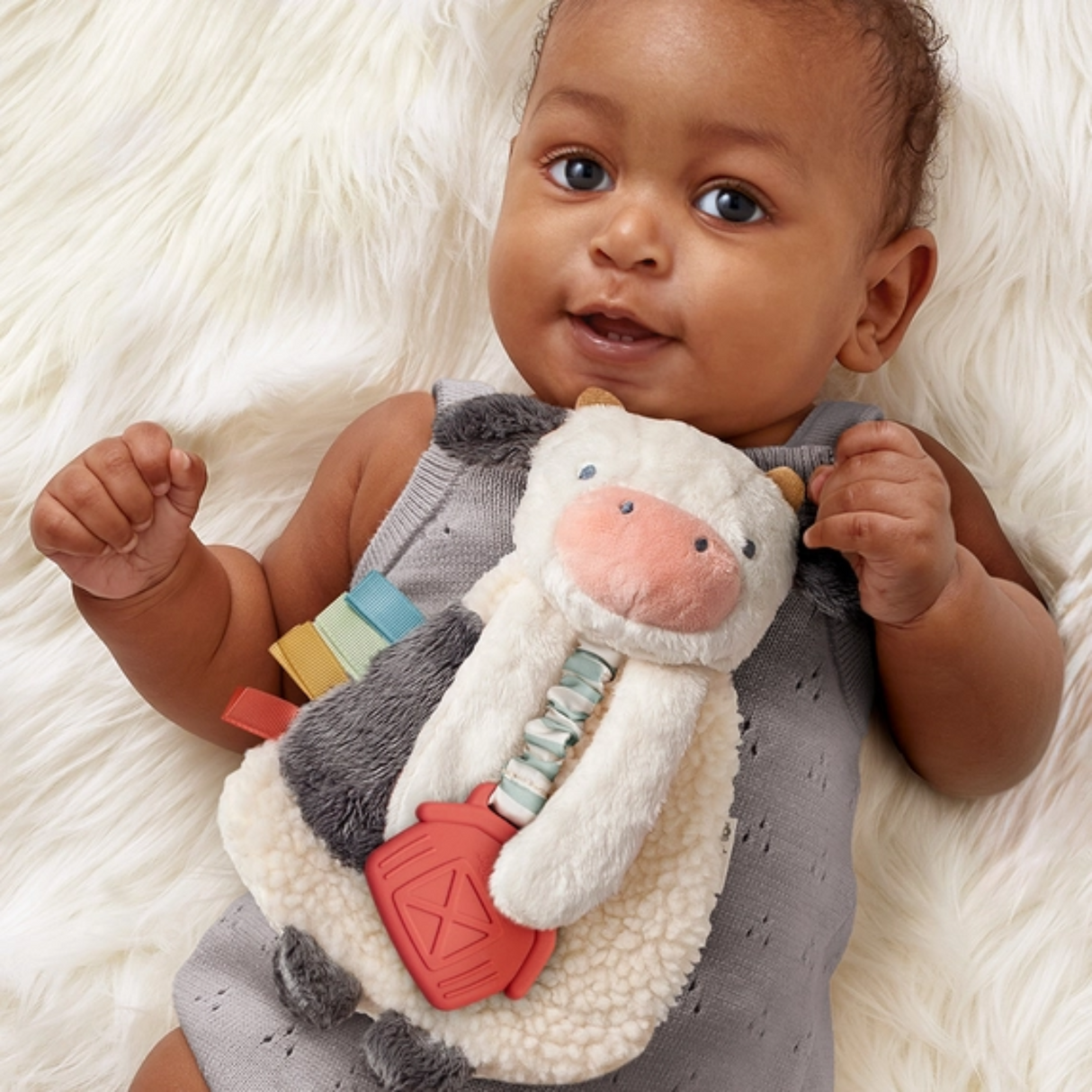 a baby holding a Cow Friends Lovey Plush