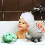 Child in a bathtub with bath toys and bubbles, smiling.