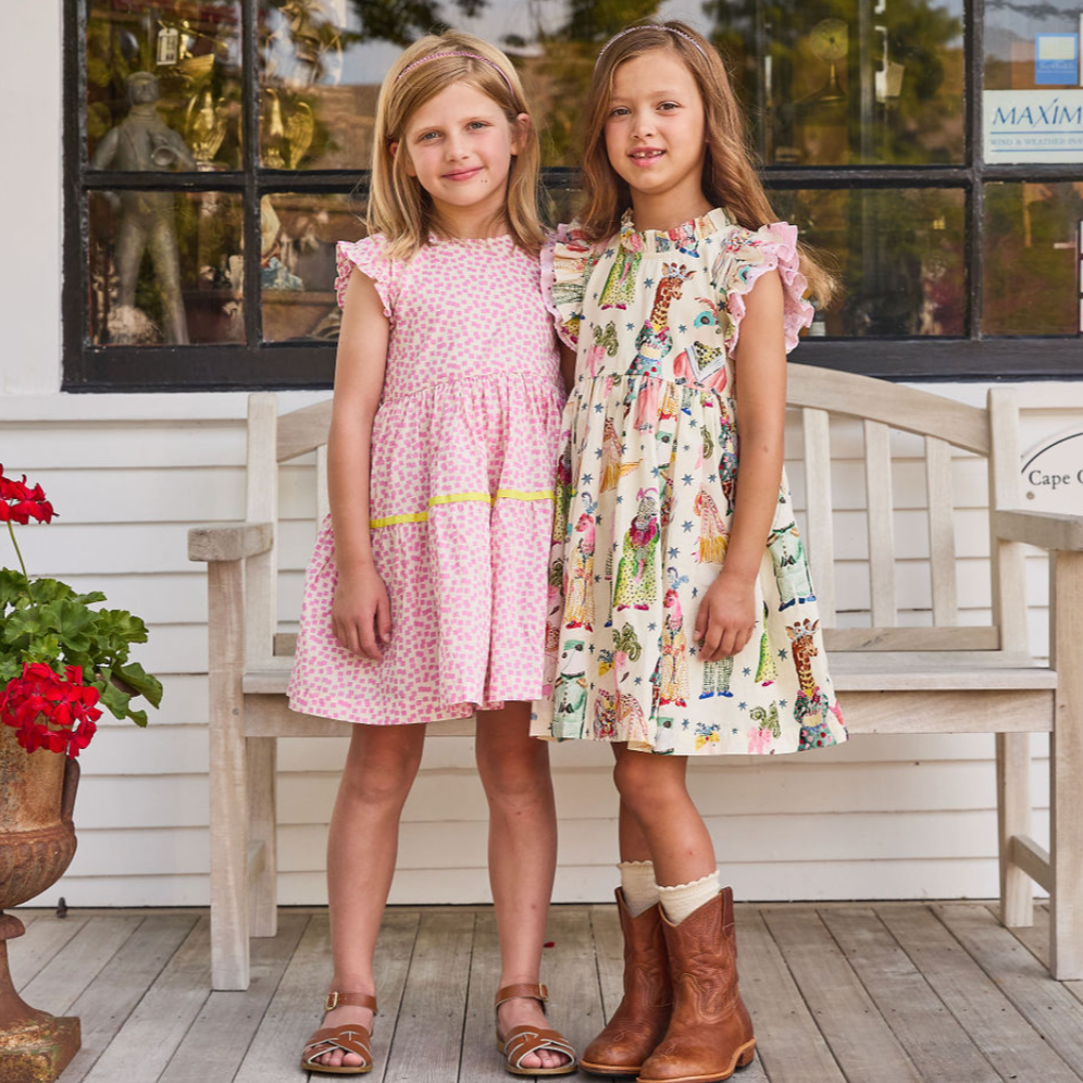 Polly Dress - Pink Mini Squares 2 girls standing in front of a bench
