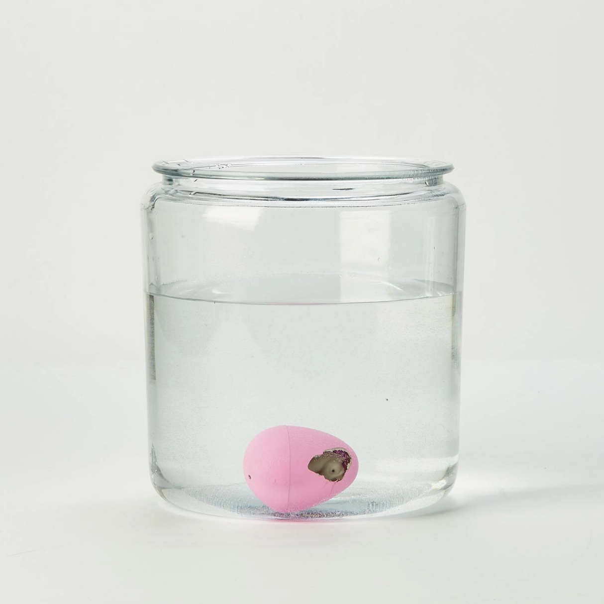 Clear glass jar with a pink ball inside on a white background
