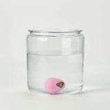 Clear glass jar with a pink ball inside on a white background