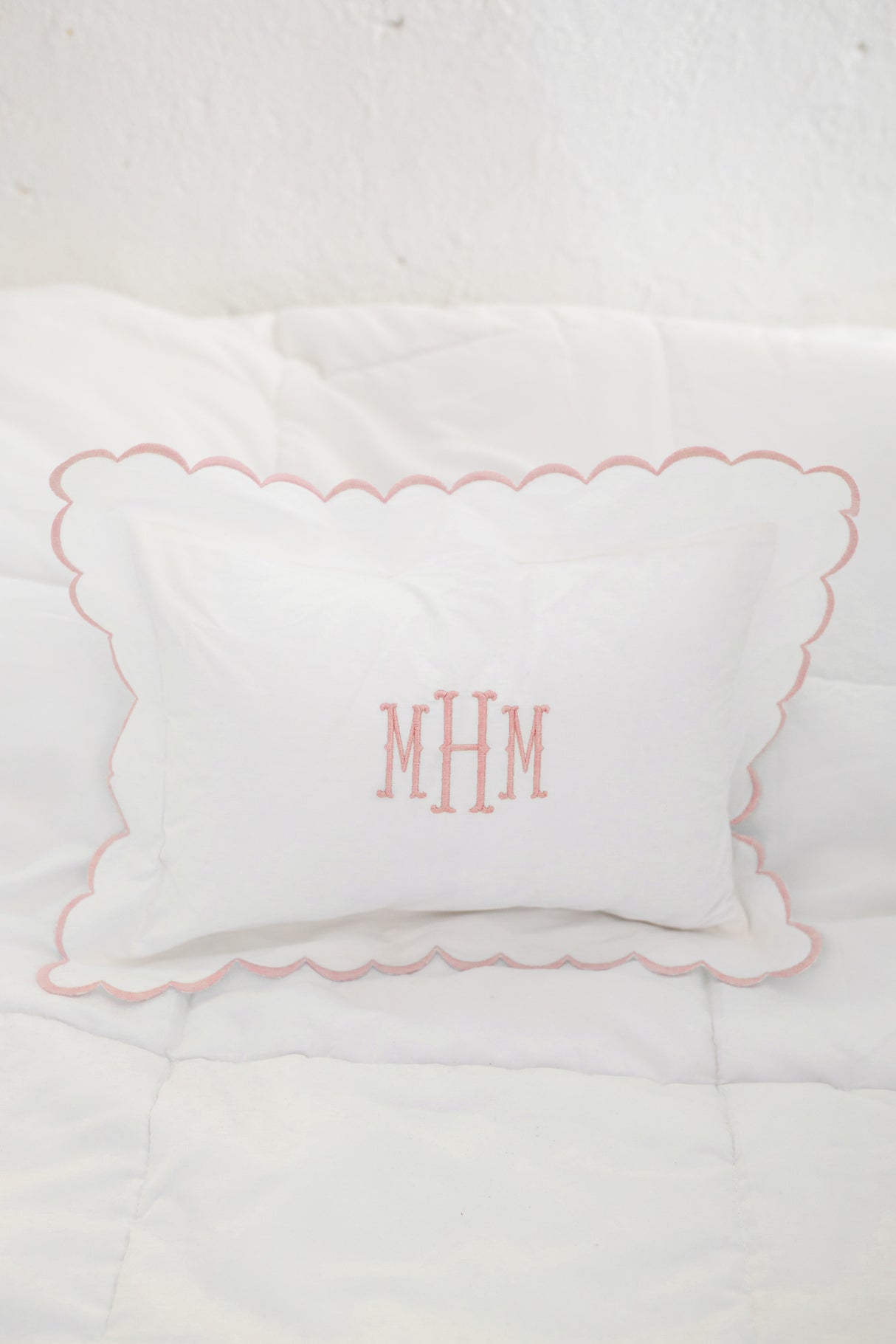 Pink scalloped pillow on white background with pink monogrammed initails