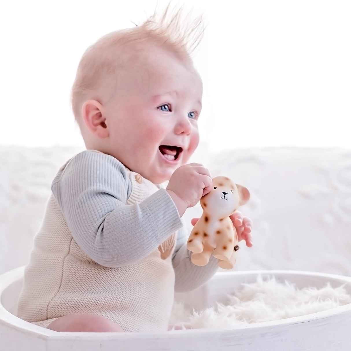 Baby holding a toy in a white crib