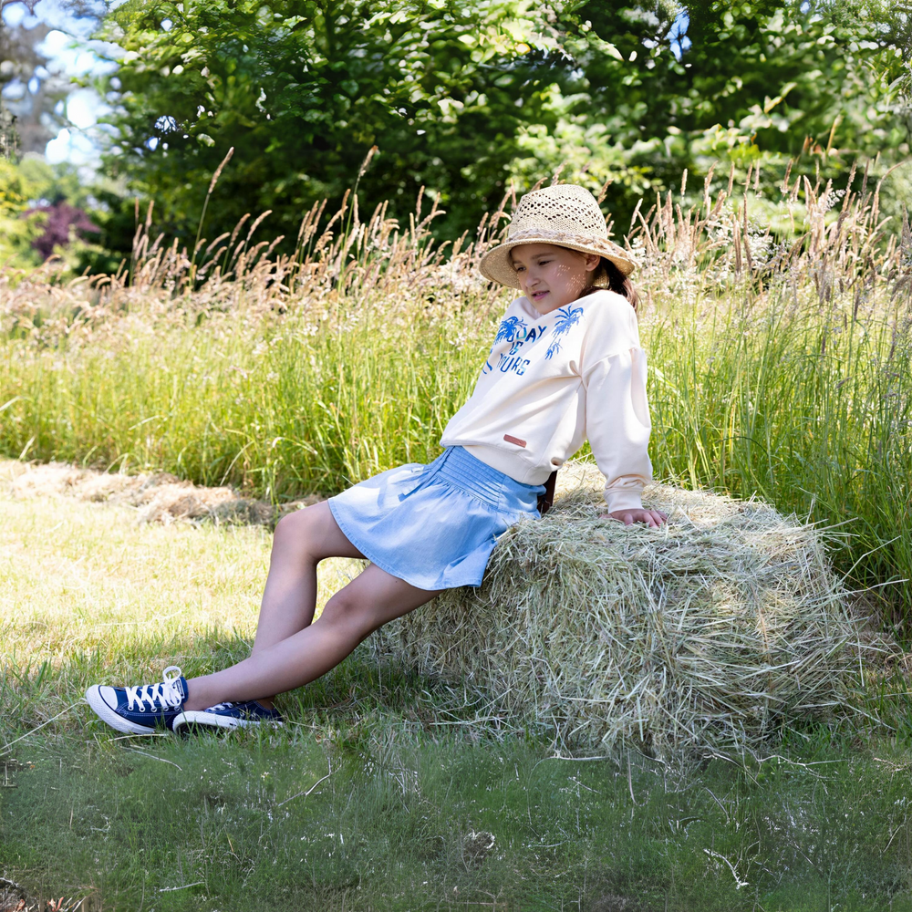 Nera Lightweight Denim Skirt a girl leaning back on a haystack