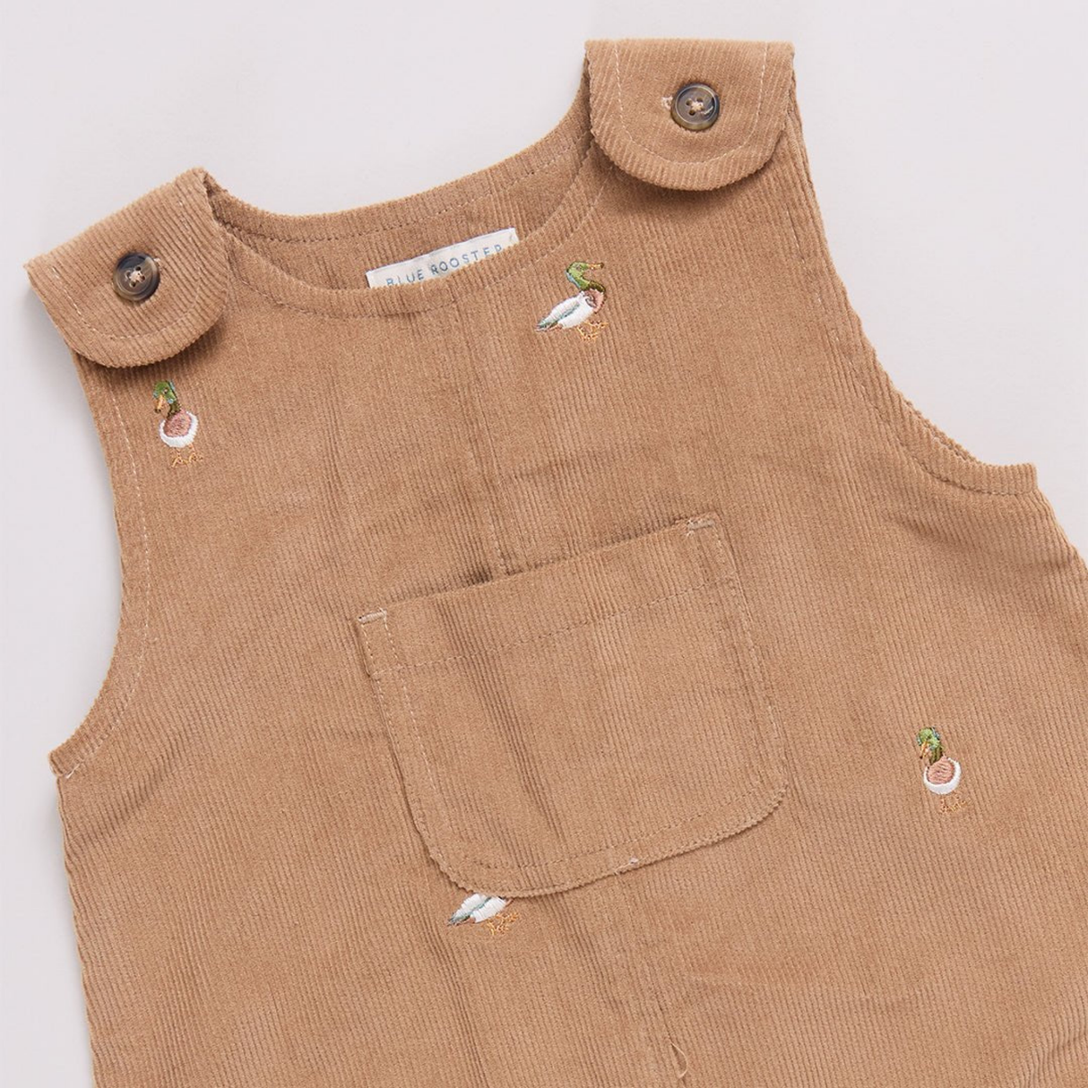 Brown corduroy overalls with button details on a white background