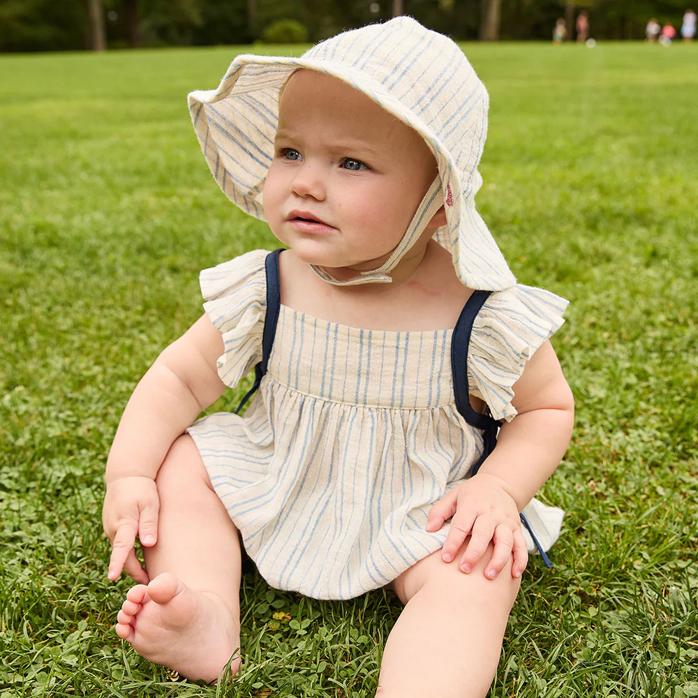 a baby girl sitting on a grass wearing Baby Ailee Bubble - Riviera Stripe