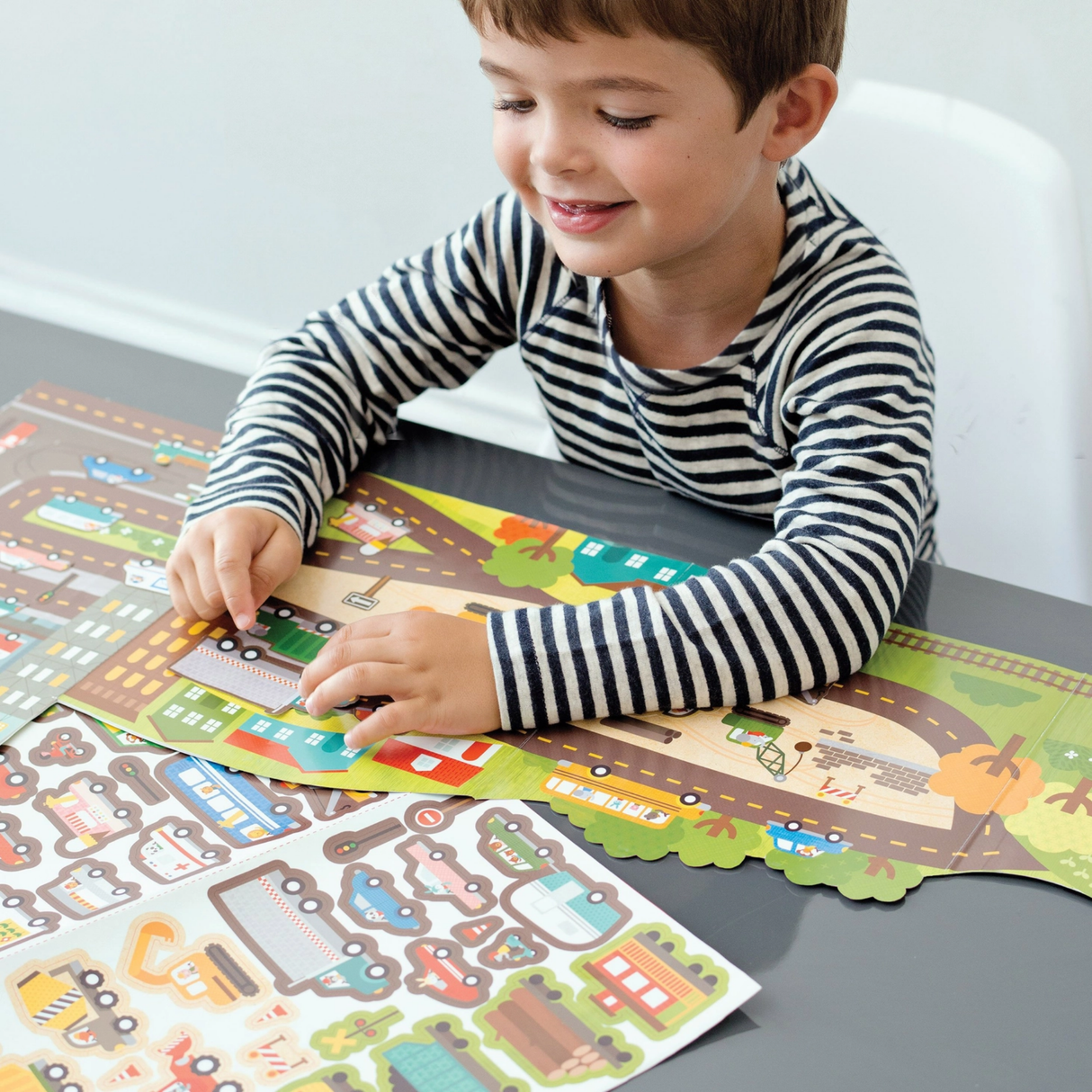 Child playing with a road-themed activity book on a table