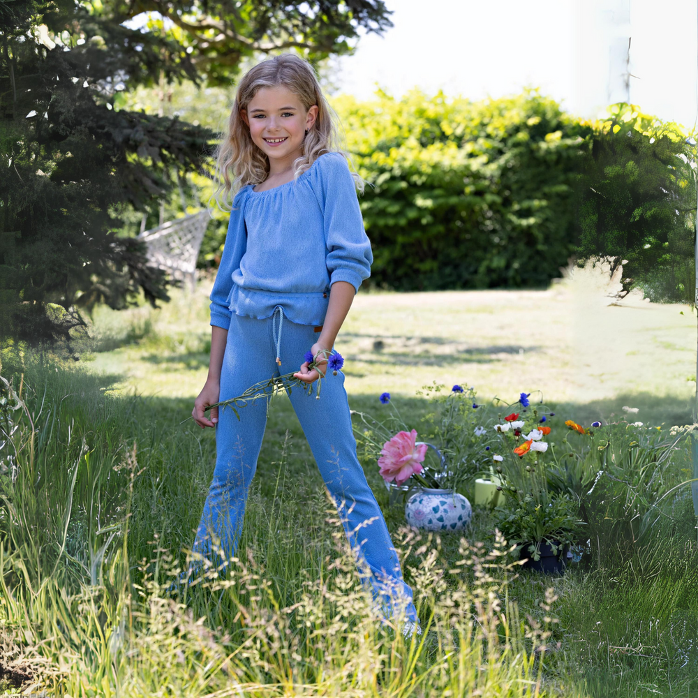 Sady Flared Pants in Parisian Blue a girl holding flowers
