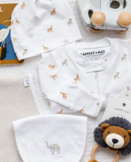 Baby clothing set with hats and a toy on a textured surface