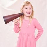 Young girl in a pink dress holding a megaphone against a light background