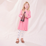 Young girl in a pink dress holding a megaphone against a plain background