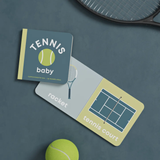 Children's book titled 'Tennis Baby' with a tennis ball and racket on a dark surface