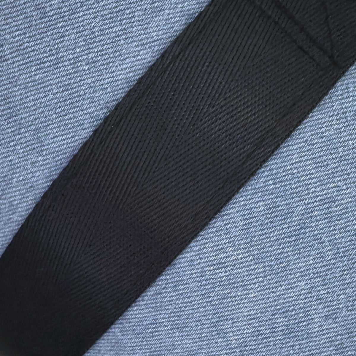 Close-up of a black strap on a textured blue fabric background