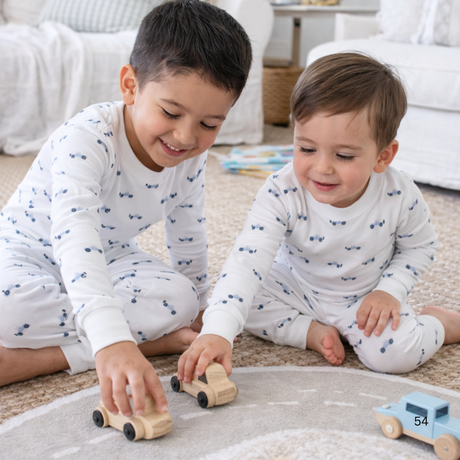 Two children playing with wooden toys on a carpeted floor.