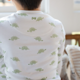 Person wearing a white shirt with green dinosaur patterns in a casual setting.