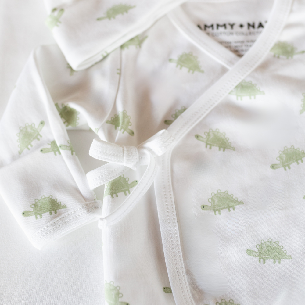 Baby outfit with green dinosaur pattern on a white background