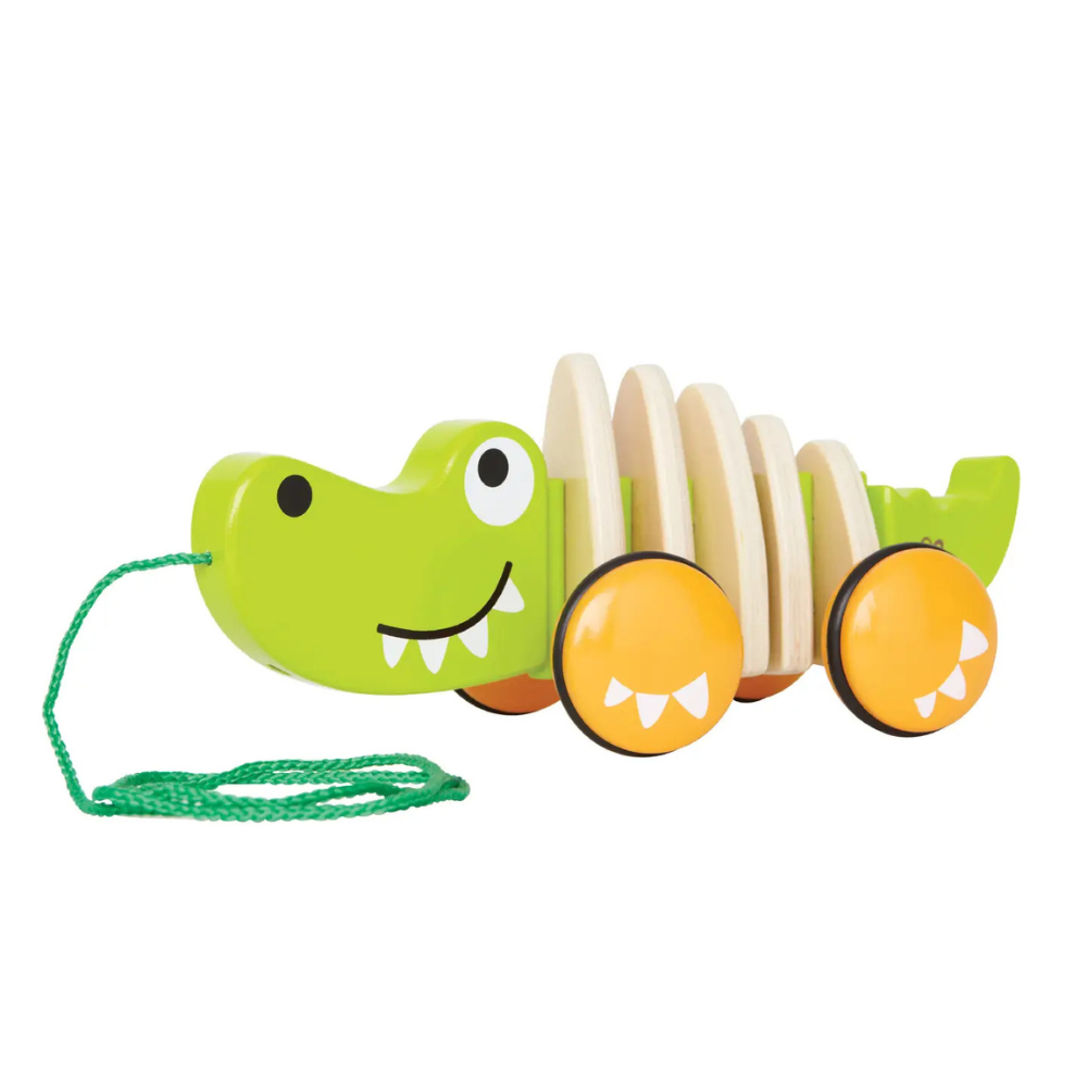 Green alligator-shaped wooden toy with orange wheels on a white background
