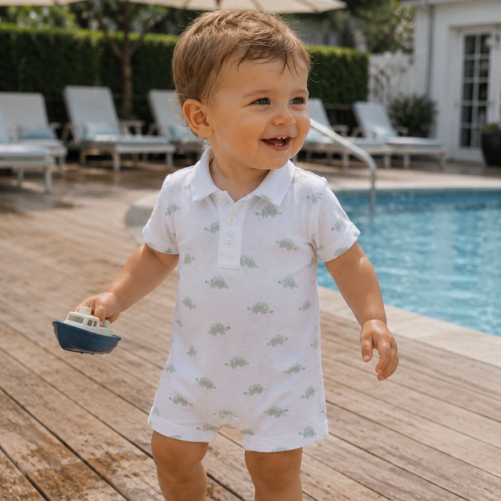 Child in a white polo shirt with a pima dino pattern by a poolside