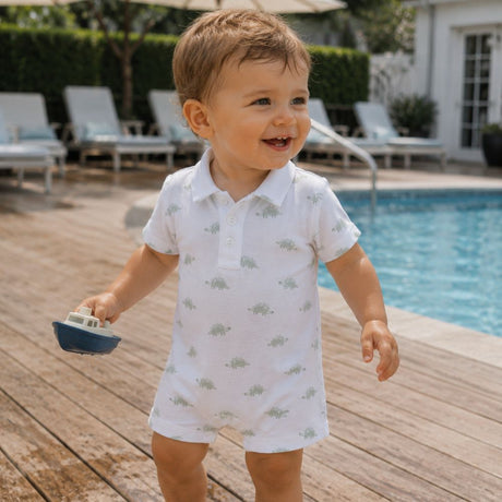 Child in a white polo shirt with a pima dino pattern by a poolside