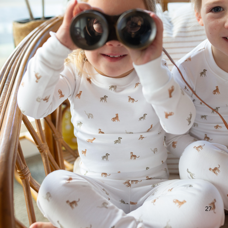 Child wearing pajamas with animal patterns, sitting on a wicker chair.