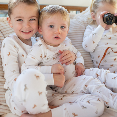 Three children in matching pajamas sitting together on a couch.